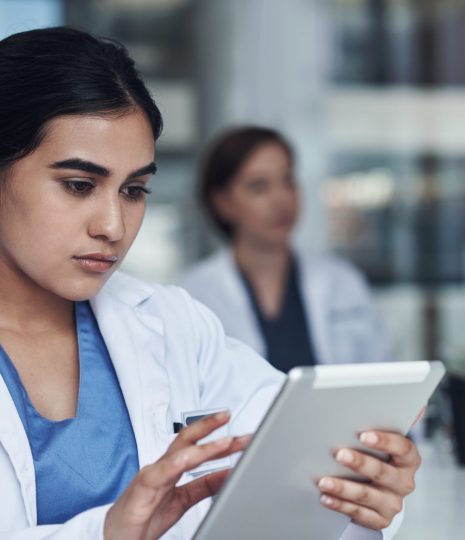 Hmm I have to attend to this immediately. Shot of a young female doctor using her digital tablet